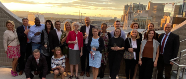 Group photo of alumni attendees of HAUS National Meeting on rooftop of Denver Art Museum with Rocky Mountains in the background